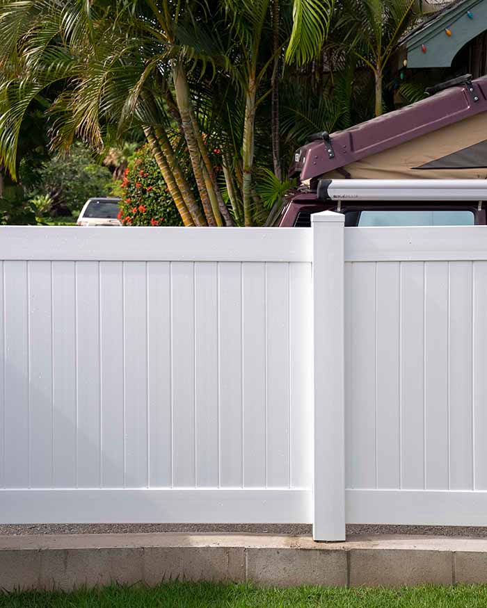 white vinyl privacy fence by tropical trees